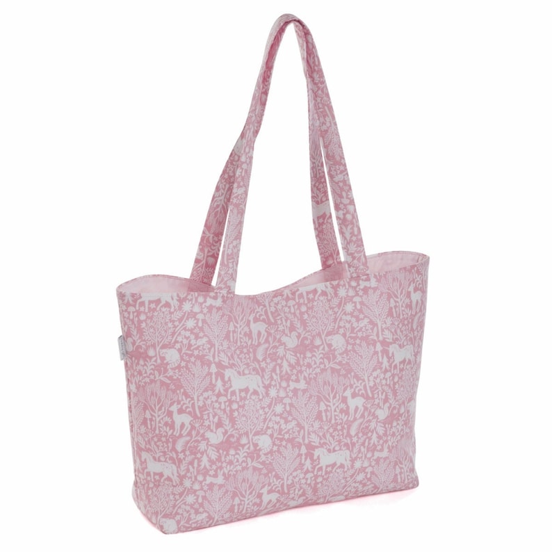 May include: A pink tote bag with a white woodland animal print. The bag has two handles and a wide base.