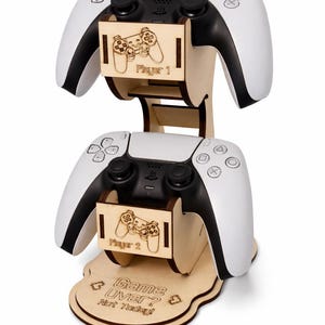 May include: Wooden gaming controller stand with two white and black controllers. The stand has two levels with Player 1 and Player 2 labels. The base reads "Game Over? Not Today!"
