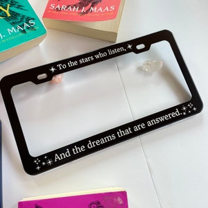 Peut inclure: Cadre de plaque d'immatriculation en m&eacute;tal noir avec le texte "To the stars who listen, And the dreams that are answered." Le cadre est d&eacute;cor&eacute; de petites &eacute;toiles blanches.