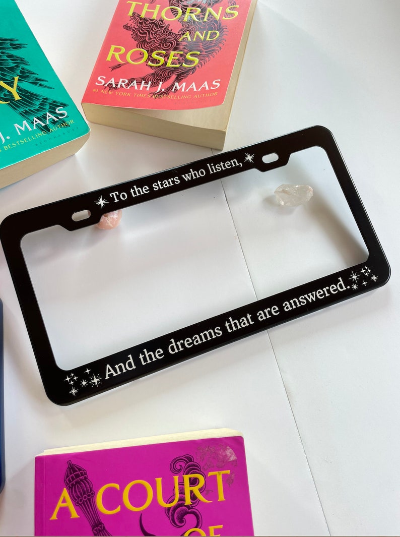 Peut inclure: Cadre de plaque d'immatriculation en m&eacute;tal noir avec le texte "To the stars who listen, And the dreams that are answered." Le cadre est d&eacute;cor&eacute; de petites &eacute;toiles blanches.