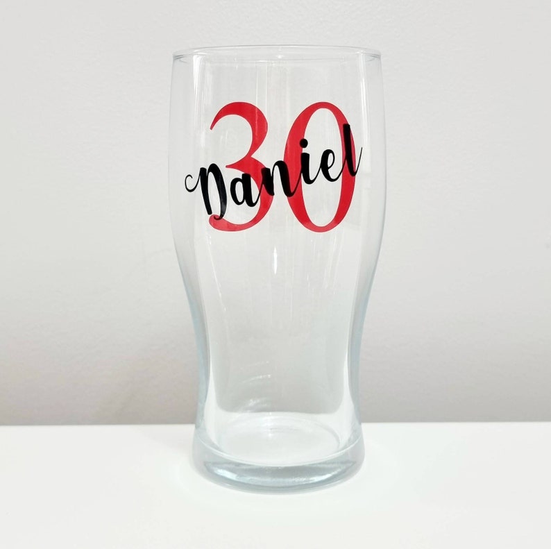 Puede incluir: Una jarra de cerveza de vidrio transparente con el n&uacute;mero 30 en rojo y el nombre "Daniel" en letras negras.