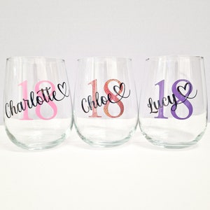 May include: Three clear stemless wine glasses with custom text. Each glass has the number "18" in a different color, with a name and heart design. The names are "Charlotte", "Chloe", and "Lucy".