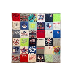 May include: A patchwork quilt made from repurposed t-shirts. The quilt is made up of 25 squares, each with a different design. Some of the designs include the words "Falcons", "Bingo", "Team 2031", and "I'm with the band!" The quilt is a great way to commemorate a special event or to show your school spirit.