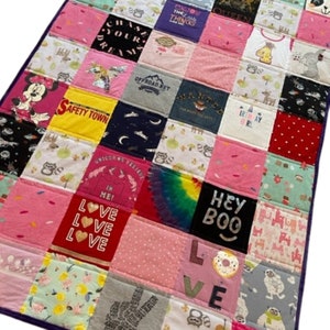 May include: A patchwork quilt made from a variety of colorful t-shirts. The quilt features a variety of designs and phrases, including "Safety Town", "Unicorns Believe", "Love", "Hey Boo", and "Birthday Girl".