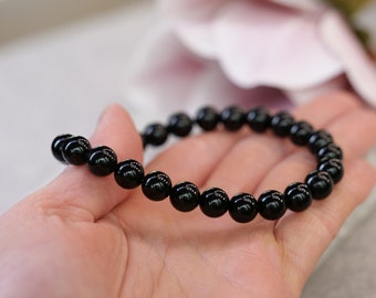 May include: A black beaded bracelet with round, shiny beads.