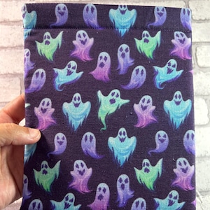 Puede incluir: Una bolsa de tela morada con un patrón repetido de fantasmas azules, verdes y morados. Los fantasmas tienen un contorno blanco y una cara sonriente blanca.