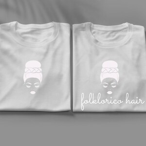 May include: Two white t-shirts with a white illustration of a woman with a bun hairstyle and the text "folklorico hair" on one shirt.