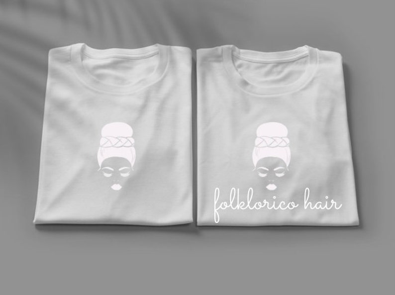 May include: Two white t-shirts with a white illustration of a woman with a bun hairstyle and the text "folklorico hair" on one shirt.
