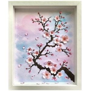 May include: A framed artwork featuring a branch of cherry blossoms. The blossoms are pink and white, with a dark brown branch against a watercolor background of pink, blue, and purple. The frame is white.