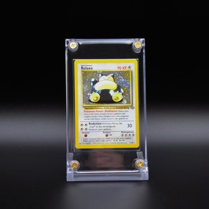 Op de afbeelding: Een gele en blauwe Pok&eacute;mon-kaart met Relaxo, een grote, ronde, blauwe Pok&eacute;mon met een gele buik. De kaart zit in een doorzichtige plastic hoes met gouden accenten. De tekst op de kaart luidt "Pokemon Power: Dickschnauber 90 KP".