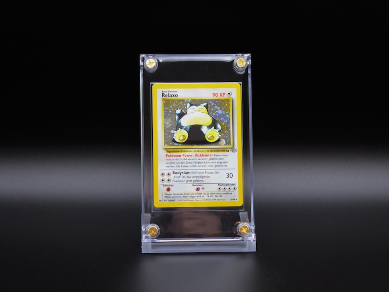 Op de afbeelding: Een gele en blauwe Pok&eacute;mon-kaart met Relaxo, een grote, ronde, blauwe Pok&eacute;mon met een gele buik. De kaart zit in een doorzichtige plastic hoes met gouden accenten. De tekst op de kaart luidt "Pokemon Power: Dickschnauber 90 KP".