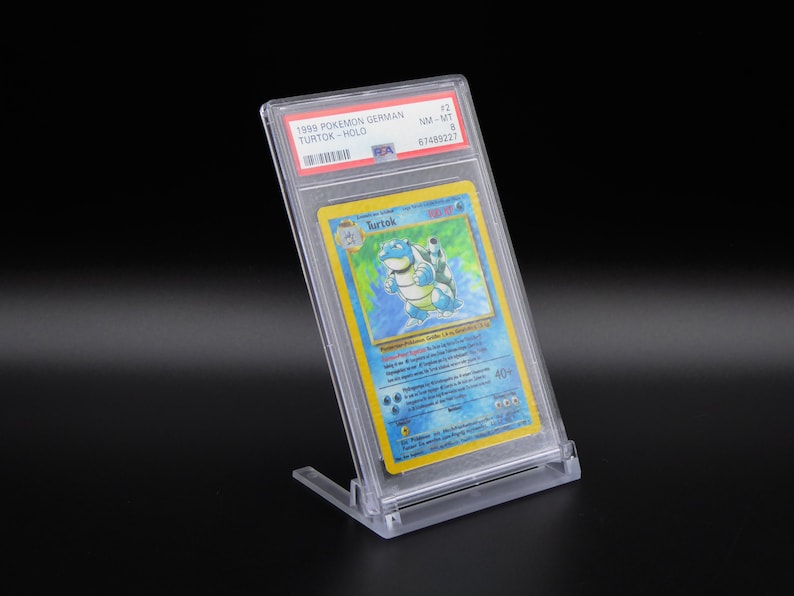 Op de afbeelding: Een beoordeelde Pok&eacute;mon-kaart in een beschermende hoes. De kaart is een Duitse versie van de Pok&eacute;mon Squirtle, een blauw schildpadachtig wezen met een schild. De kaart is beoordeeld als NM-MT 8 door een onafhankelijk beoordelingsbedrijf.