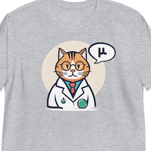 May include: A grey t-shirt featuring a cartoon illustration of a cat dressed as a scientist. The cat is wearing a lab coat, glasses, and a tie, and is holding a beaker. A speech bubble above the cat's head says "μ".