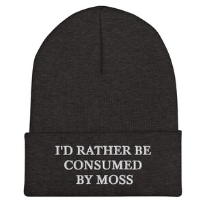 May include: A dark gray beanie with the text "I'd rather be consumed by moss" embroidered in white.