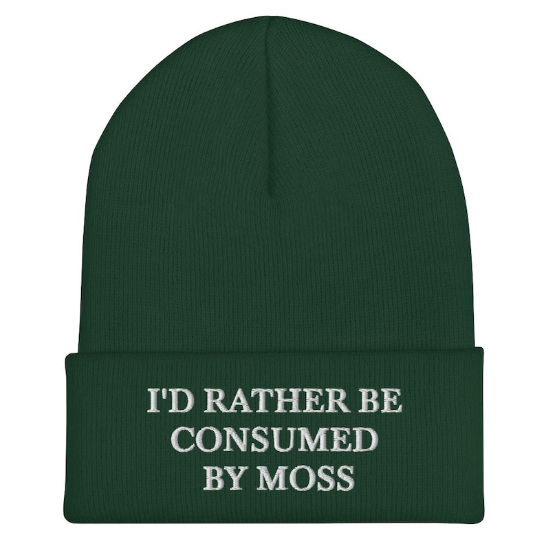 May include: A dark green beanie with the text "I'd rather be consumed by moss" embroidered in white.