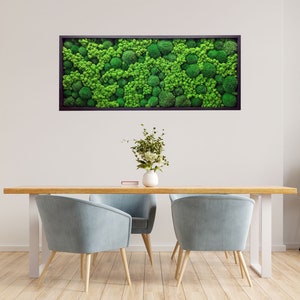 Op de afbeelding: Een rechthoekig wandkunstwerk met een dichte opstelling van geconserveerd mos in diverse tinten levendig groen, gevat in een donkere, dunne lijst. Het mos heeft een getextureerd, afgerond en organisch uiterlijk over het gehele oppervlak.