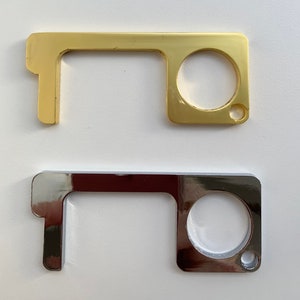 May include: Two door openers, one gold and one silver. Both have a loop handle and a round opening for pushing buttons.