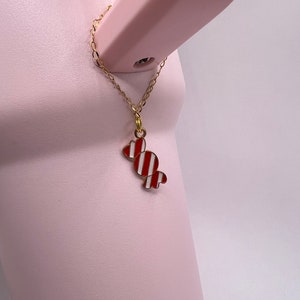 Op de afbeelding: Een roze waterkoker met een gouden ketting en een rode en witte snoephanger.