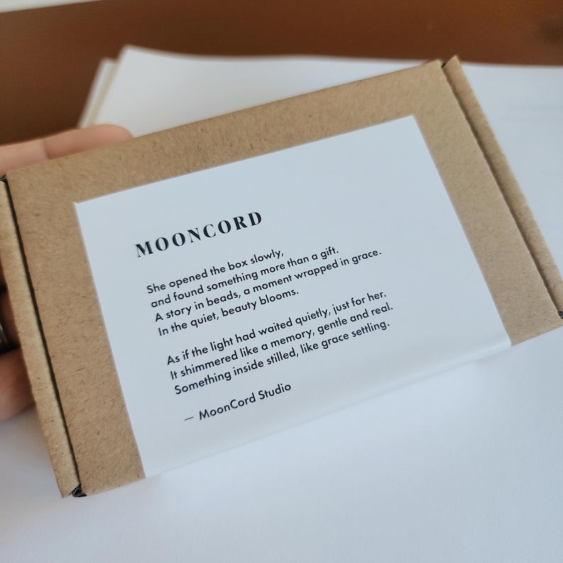 a hand holding a brown cardboard box with a white label that contains text. The label appears to be a description or description of the contents of the box.