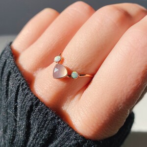 May include: A rose gold ring with a heart-shaped chalcedony gemstone and two smaller opal gemstones.