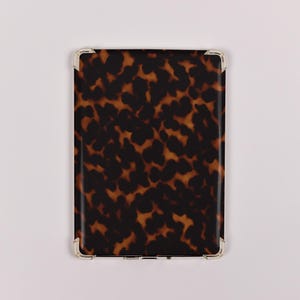 May include: A rectangular case with a tortoiseshell pattern in shades of brown and black. The corners are reinforced with silver-colored metal. The case is likely designed to hold a tablet or similar electronic device.