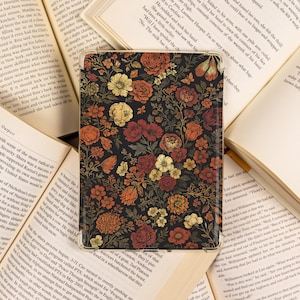 May include: A floral pattern adorns a tablet case, featuring a dark background with red, orange, yellow, and white flowers. The case is open, revealing the screen, and rests on open books.