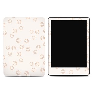 May include: A cream-colored tablet case and a tablet with a black screen. The case and the tablet border are decorated with a repeating pattern of light brown smiley faces. The case is on the left, and the tablet is on the right.