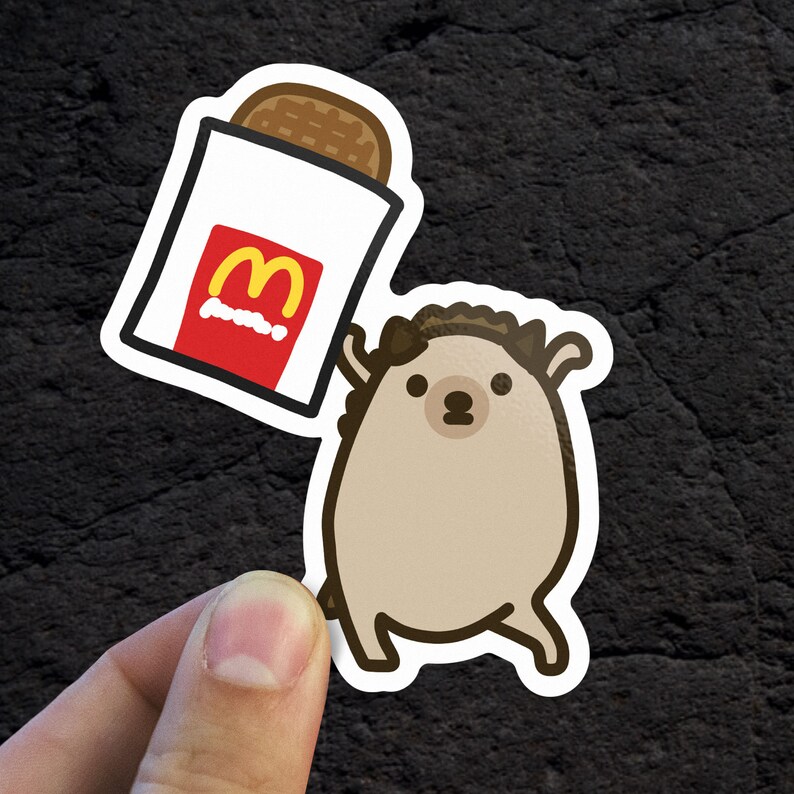 May include: A cartoon hedgehog holding a red and yellow McDonald's bag with a french fry inside. The hedgehog is brown with a white belly and has a friendly expression.