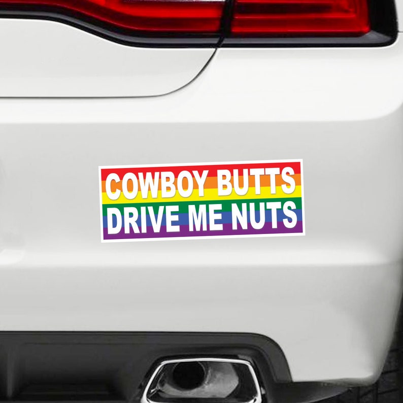 May include: A rainbow-colored bumper sticker with the text "COWBOY BUTTS DRIVE ME NUTS".