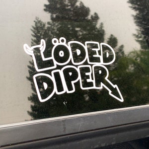 May include: White vinyl sticker on a car window with the text "LÖDED DIPER" in a bold, cartoon-like font. The sticker features a small cartoon bull's head with horns.