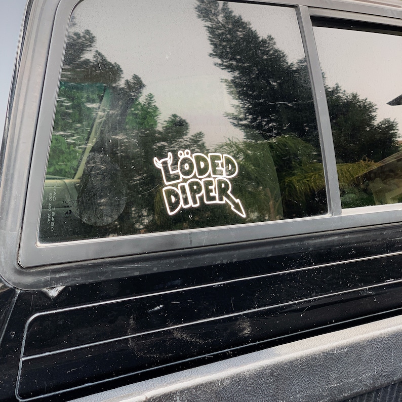 May include: A black truck with a white sticker on the back window that says "L&Ouml;DED DIPER" with a devil's horns and a lightning bolt.