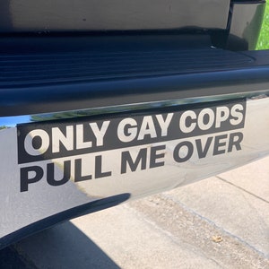 Puede incluir: Una pegatina negra en un parachoques plateado de una camioneta negra dice "ONLY GAY COPS PULL ME OVER".
