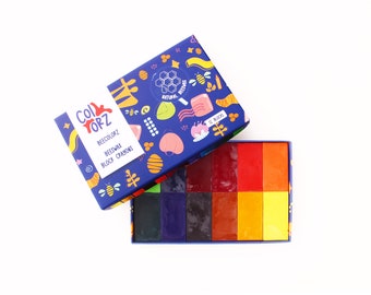 Puede incluir: Una caja de 12 crayones de cera de abeja en bloques de varios colores, incluyendo rojo, naranja, amarillo, verde, azul y morado. La caja es azul con un diseño colorido que presenta abejas, flores y panales. El texto en la caja dice "Beecolorz Beeswax Block Crayons".