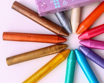 Puede incluir: Una colección de ceras metálicas en varios colores, incluyendo dorado, bronce, plateado, naranja, rojo y azul, dispuestas en un patrón circular. Las ceras se muestran con una caja parcialmente visible con las palabras "Natural Mica" y "Beeswax".