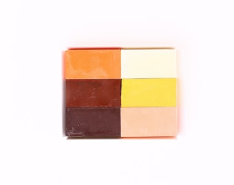 Puede incluir: Seis bloques rectangulares de cera en diferentes colores: naranja, marrón, marrón oscuro, amarillo, marrón claro y melocotón.