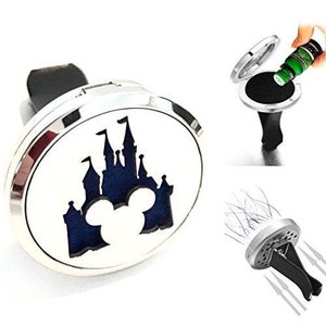 May include: Silver car air freshener with a white face featuring a blue castle design with Mickey Mouse ears. The air freshener is shown with a black clip and a separate image of essential oil being applied.