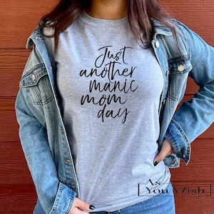 May include: A gray t-shirt with the text "Just another manic mom day" in black lettering.