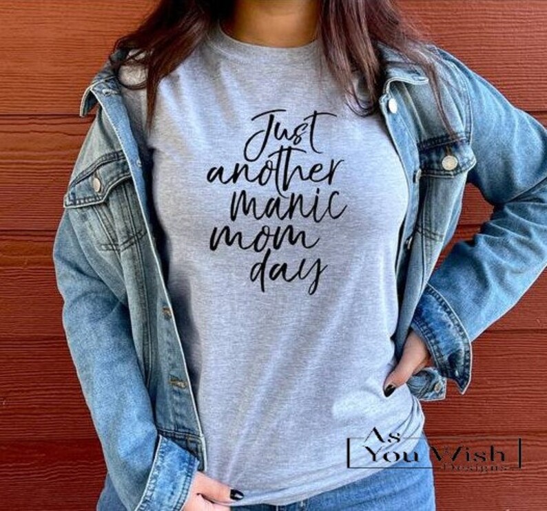 May include: A gray t-shirt with the text "Just another manic mom day" in black lettering.