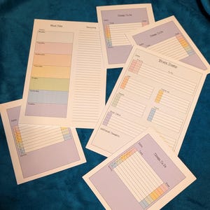 May include: A selection of printed planner sheets, including "Meal Plan," "Shopping," and "Things To Do." The sheets have pastel-coloured sections and lined spaces for notes and tasks. The design is intended for organisation and planning.