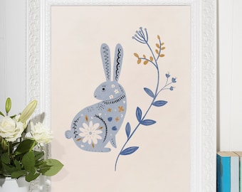 Puede incluir: Un conejo azul con patrones florales se sienta en una rama con hojas azules y marrones. El conejo está rodeado de un marco blanco.