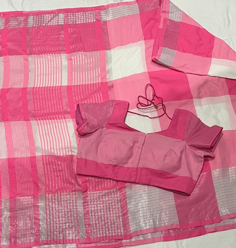 May include: A pink and white checkered saree with a matching pink blouse. The saree has a silver thread woven into the fabric.