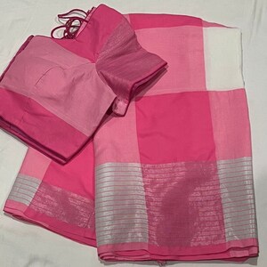 May include: A pink and white checkered saree with silver trim. The saree has a matching pink blouse.