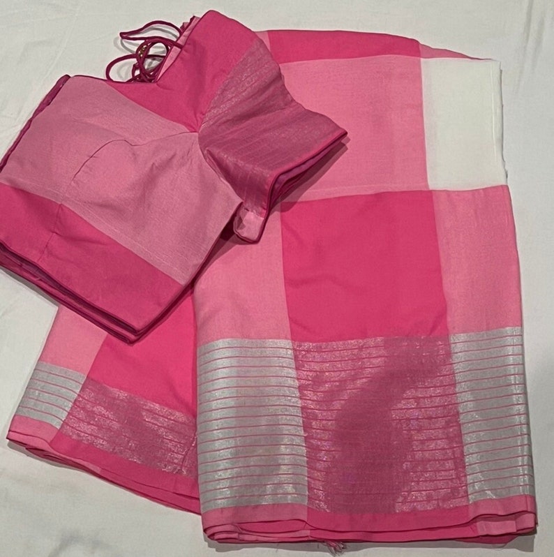 May include: A pink and white checkered saree with silver trim. The saree has a matching pink blouse.