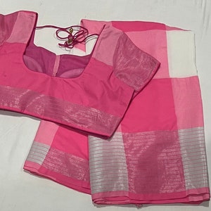 May include: A pink and white checkered saree with a silver border. The saree comes with a matching pink blouse.