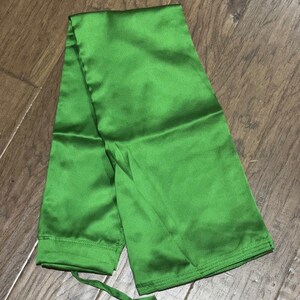 May include: A folded green satin fabric sash with a drawstring tie.