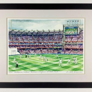May include: Watercolour painting of a cricket match at the Melbourne Cricket Ground, Australia versus England. The stadium is packed with spectators. The artwork is framed in a black frame.
