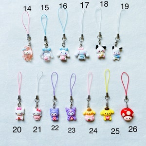 Pode incluir: Um conjunto de 12 pingentes de telefone coloridos com v&aacute;rios personagens de desenhos animados, incluindo Hello Kitty, My Melody e Pochacco. Os pingentes s&atilde;o presos a cordas coloridas e numerados de 14 a 26.