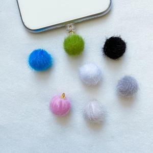 Puede incluir: Surtido de pompones esponjosos y coloridos con detalles dorados. Los pompones son de varios colores, incluyendo azul, verde, rosa, blanco, negro y gris.
