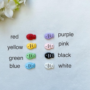 May include: Assortment of colorful fish-shaped buttons in red, yellow, green, blue, purple, pink, black, and white.