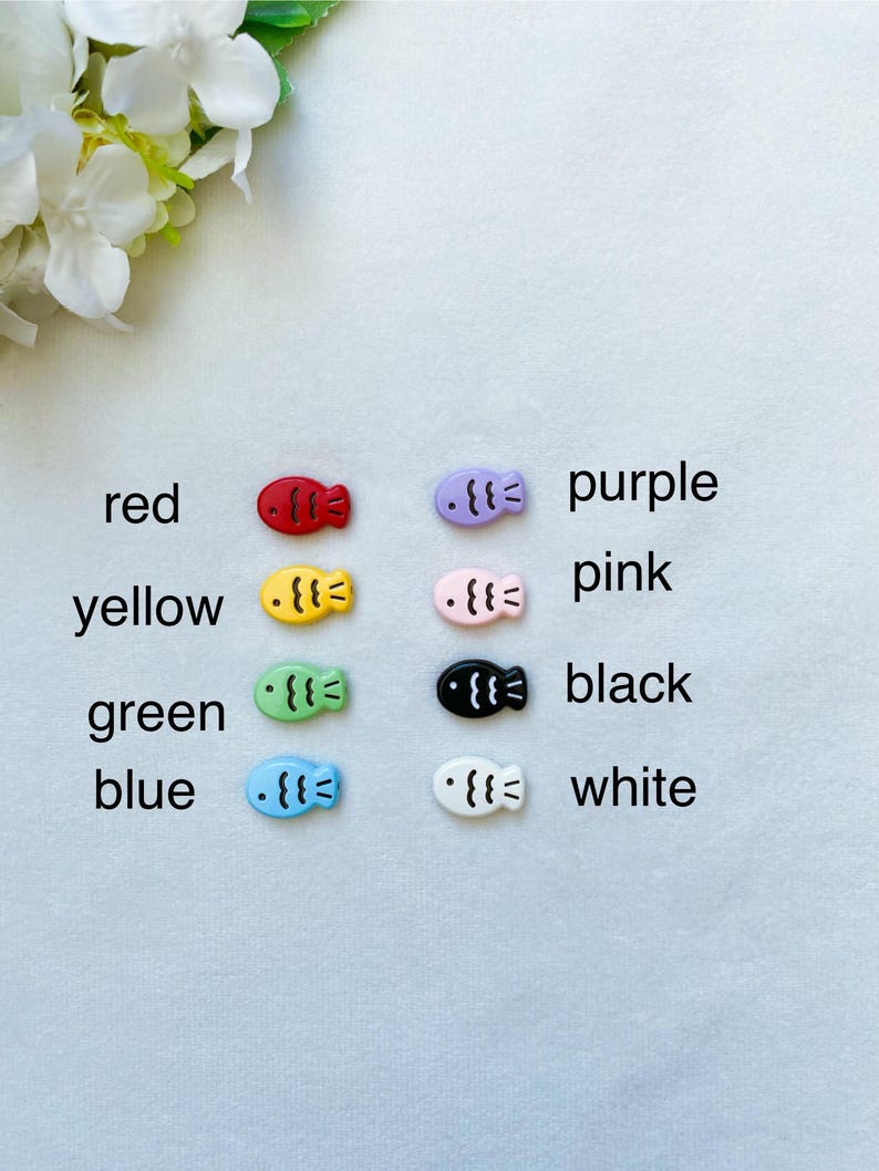 May include: Assortment of colorful fish-shaped buttons in red, yellow, green, blue, purple, pink, black, and white.